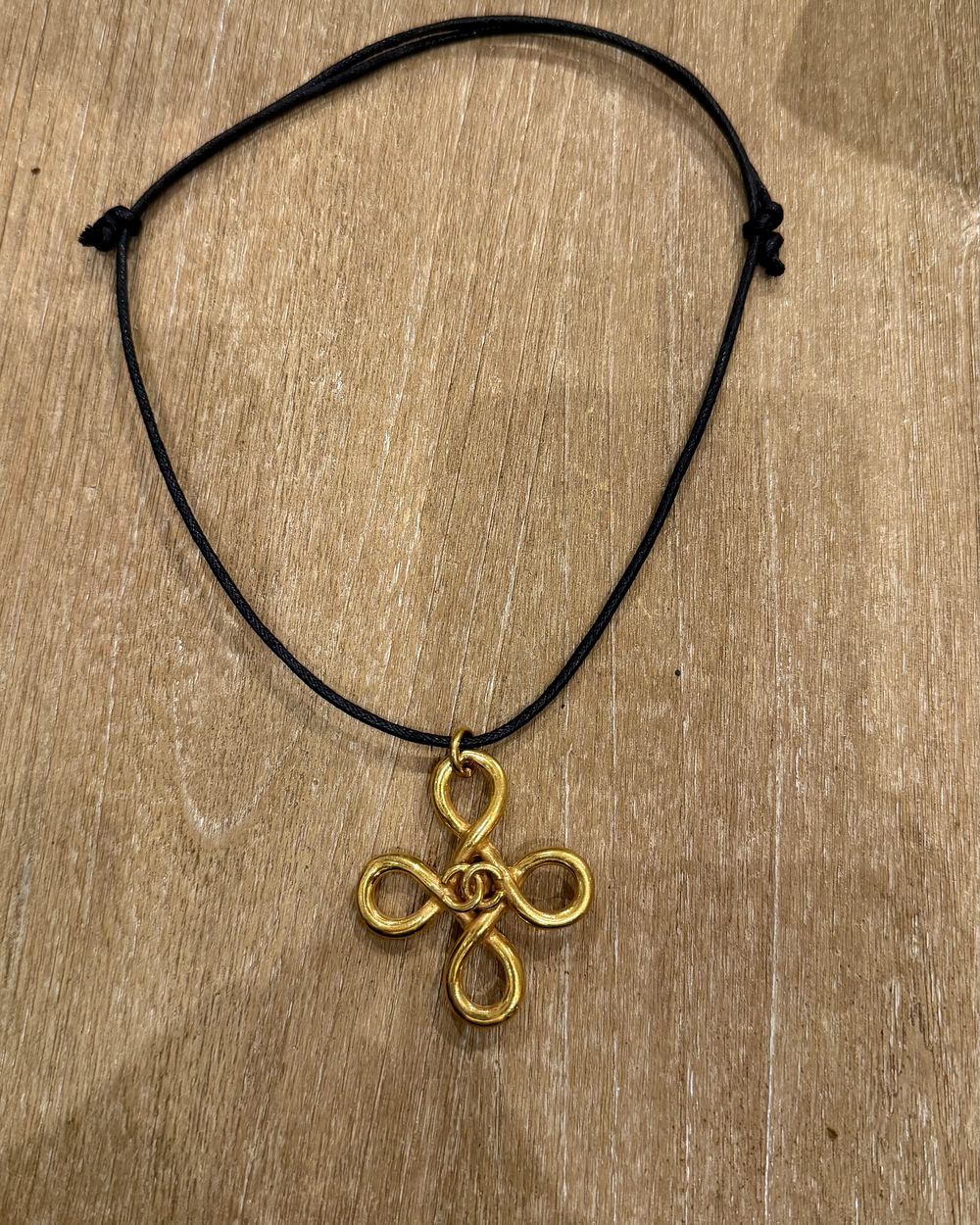 Clover Knot on cord, flat lay on oak — Maison Dorée vintage charm necklace