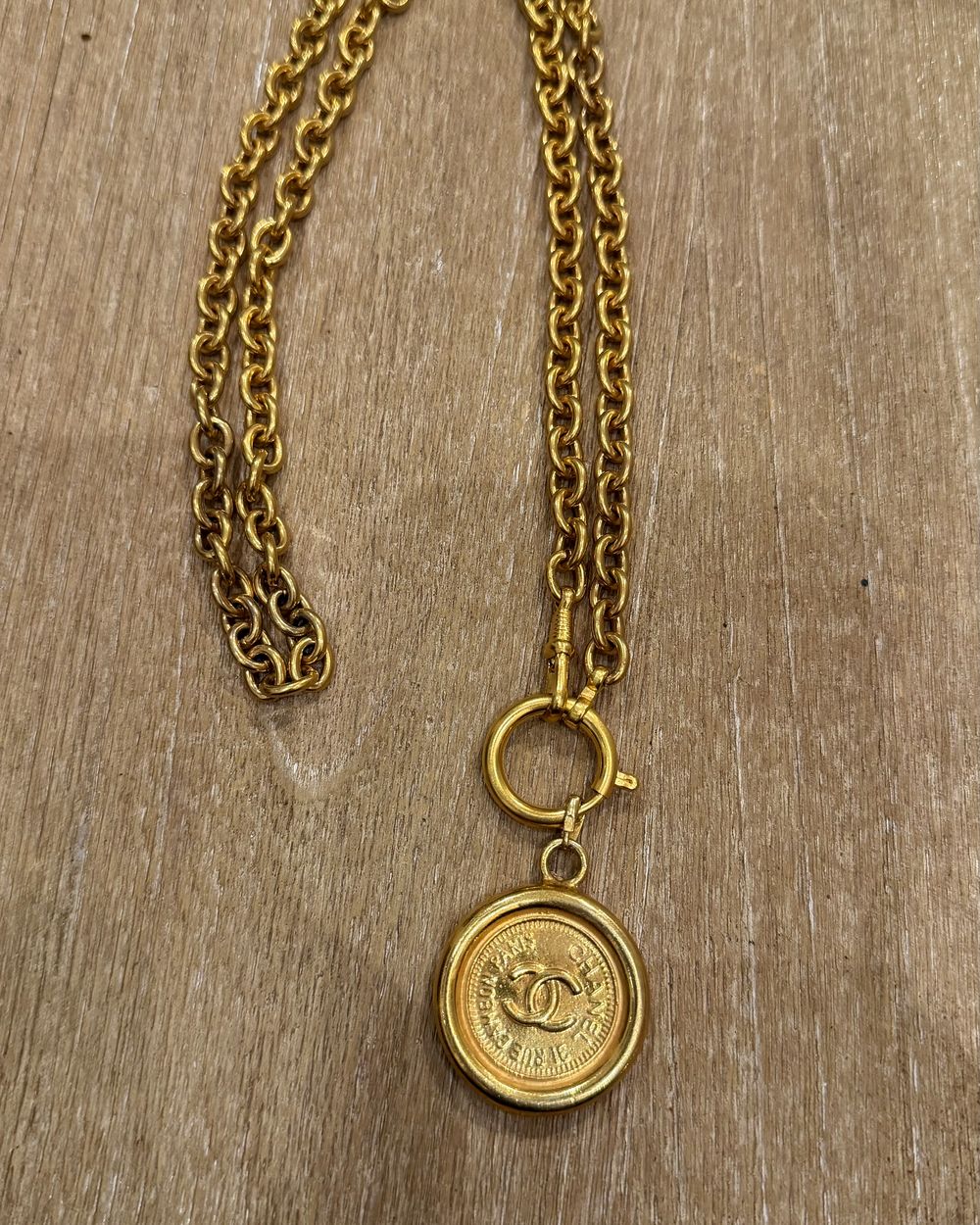Paris Coin on chain, flat lay on oak — Maison Dorée vintage charm necklace