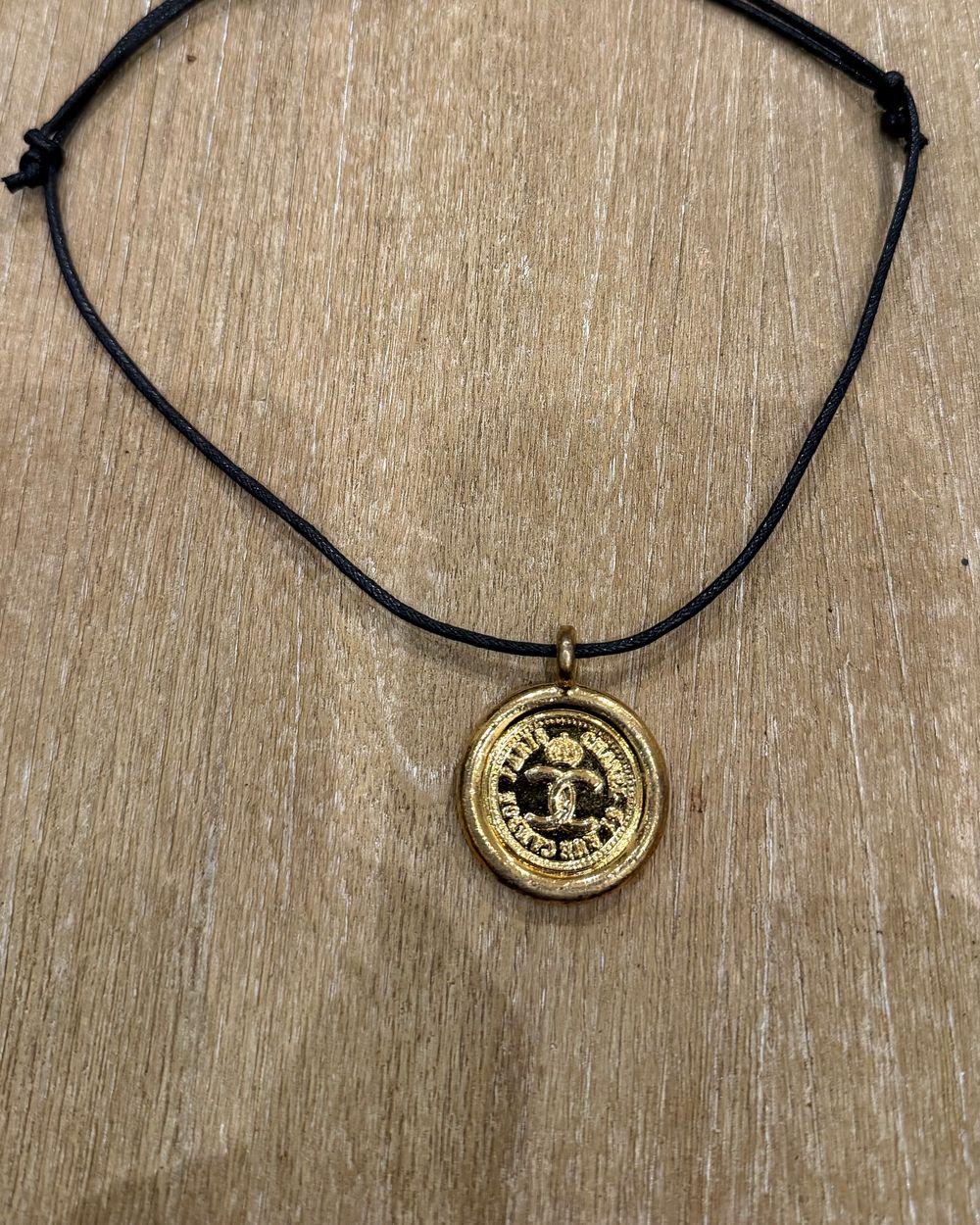 Paris Coin on cord, flat lay on oak — Maison Dorée vintage charm necklace