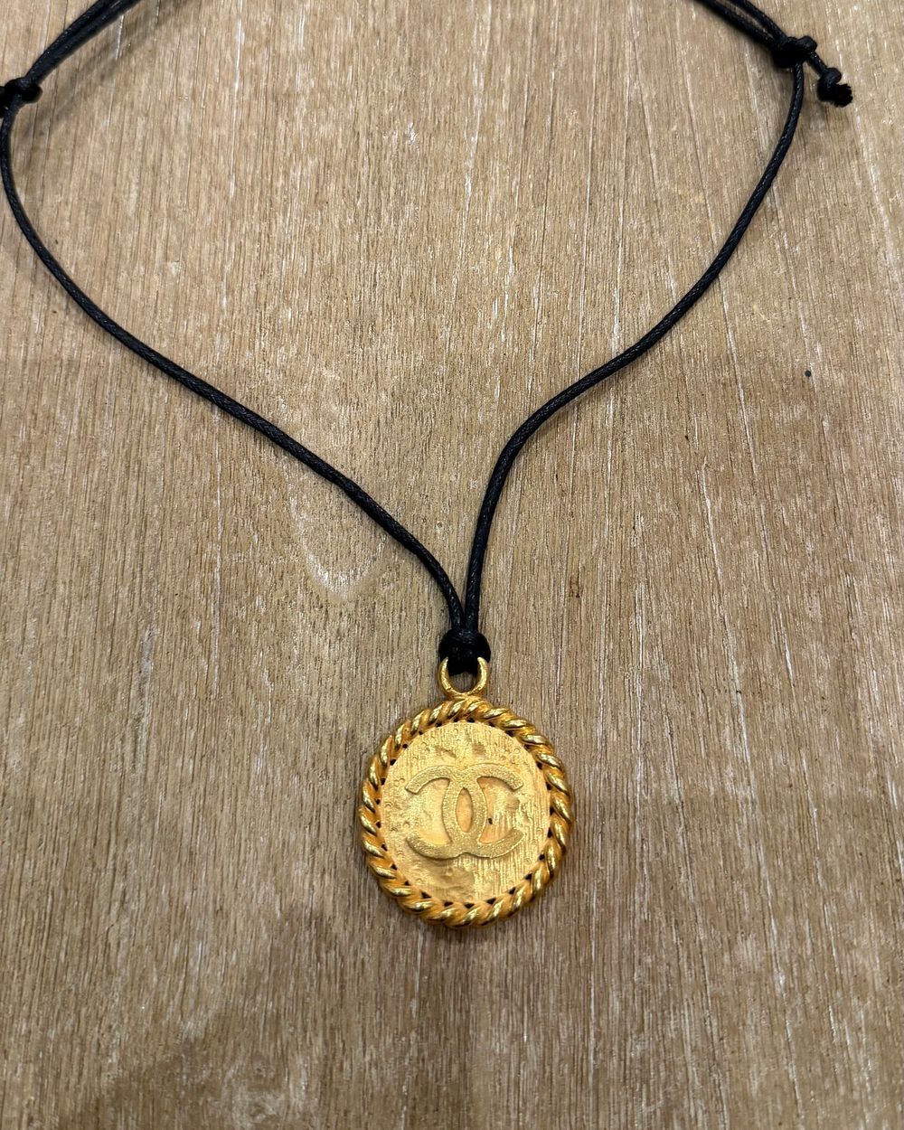 Rope Medallion on cord, flat lay on oak — Maison Dorée vintage charm necklace
